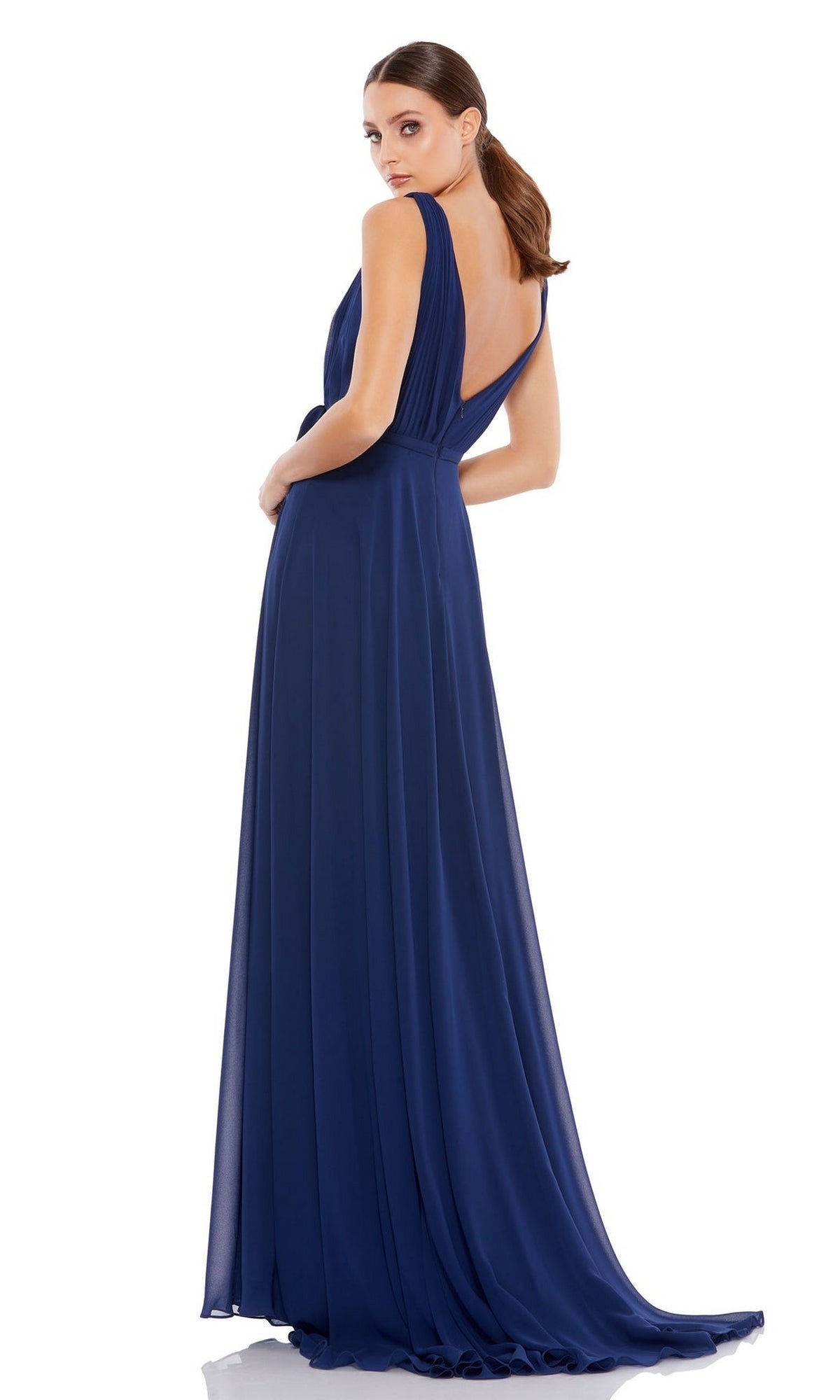 A woman wears the Mac Duggal 55283 Midnight Blue Long Formal Dress—sleeveless, floor-length, with an open back and elegant a-line skirt—standing and looking over her shoulder against a white background.